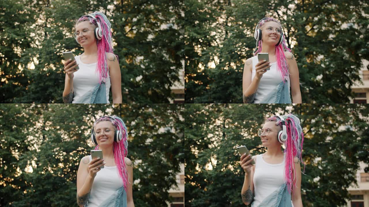 朋克女孩戴着耳机在城市公园跳舞，用智能手机玩得开心
