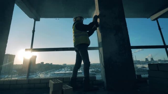 男性建造师正在建筑工地打磨一根柱子