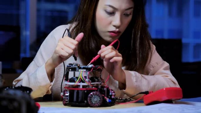 十几岁的女性在深夜工作的夜晚为学校机器人俱乐部的全功能可编程机器人工作。教育，技术，团队合作，工作到