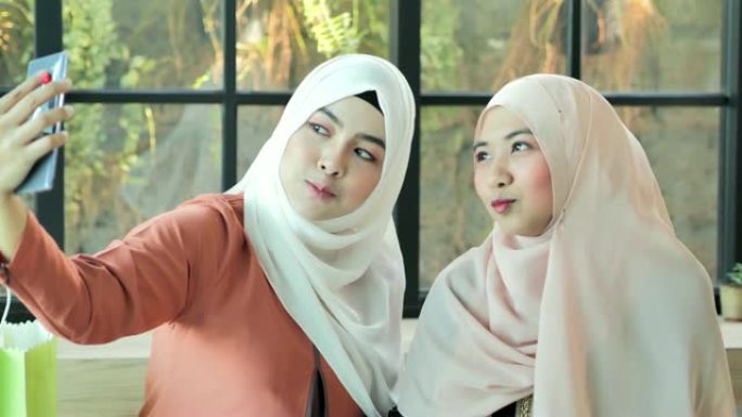 两个快乐的年轻穆斯林妇女用手机自拍。阿拉伯青年