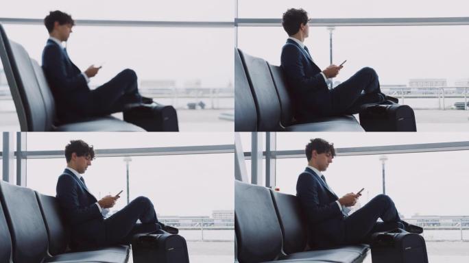 用手机拍摄坐在机场候机室带着行李的商人的聚焦镜头-慢动作拍摄