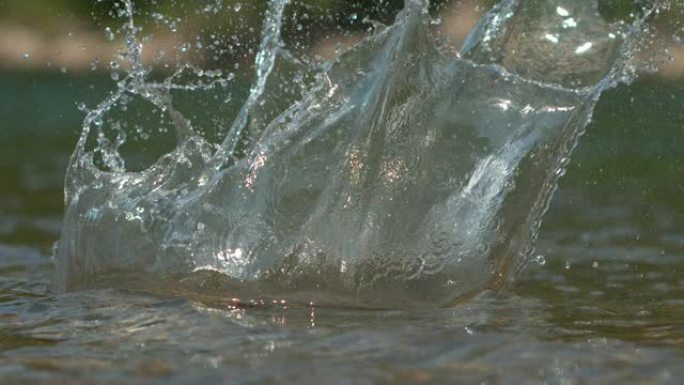 宏观: 卵石掉入河中后，晶莹剔透的水在电影中飞溅。