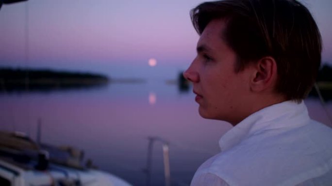 湖上浪漫的日落。年轻人从船上看风景