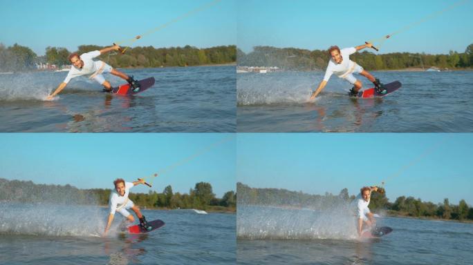 慢动作: 英俊的金发男子在滑水板上飞驰而过相机时微笑。