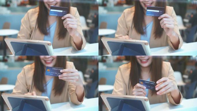 4k镜头亚洲女性使用信用卡和平板电脑在线购物的场景在百货公司的共同工作空间无现金，科技钱包和在线支付