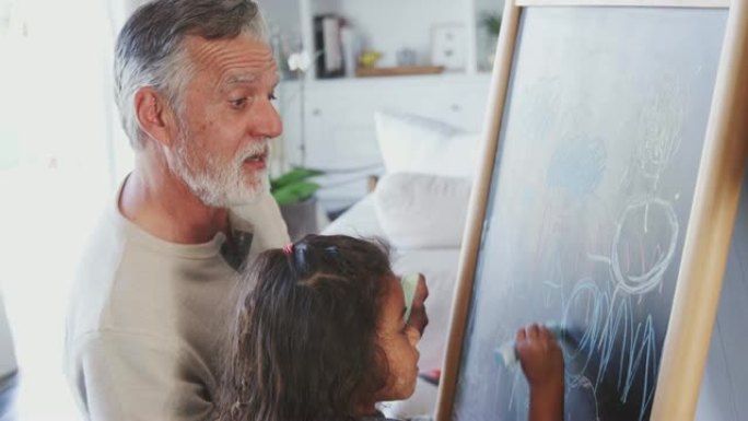 老人和他的小孙女在家在黑板上画画