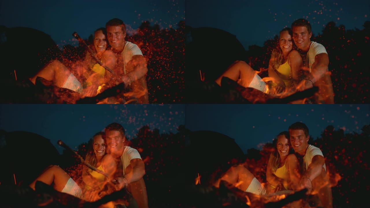 特写镜头，dop: 快乐的夫妇坐在篝火旁享受浪漫的夜晚。