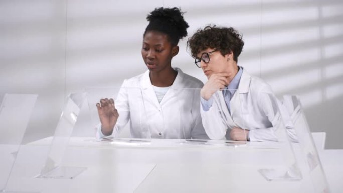 两名女性科学家在AR触摸屏上讨论计算机模型