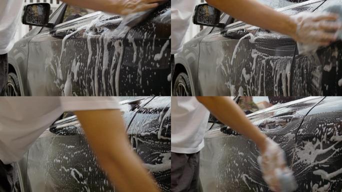 Dci 4k分辨率亚洲男人的手正在使用海绵和泡沫清洗黑色汽车和清洁脏灰尘。