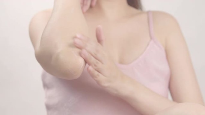亚洲成年女性用手在肘部和手上涂抹保湿霜。身体护理概念。美容化妆品