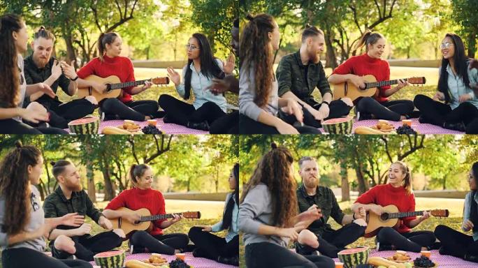 在阳光明媚的秋天，当美丽的女孩在公园野餐时弹吉他时，顽皮的年轻人正在唱歌和移动手。乐趣和音乐概念。