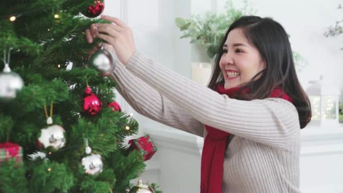 迷人的亚洲年轻女孩在客厅装饰圣诞树。