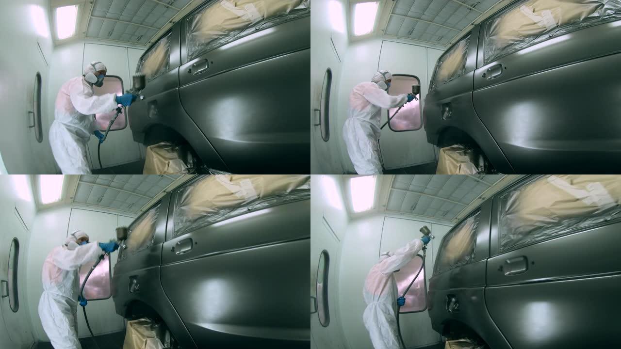 男技术员正在车库里给一辆汽车着色。工业喷漆工艺。