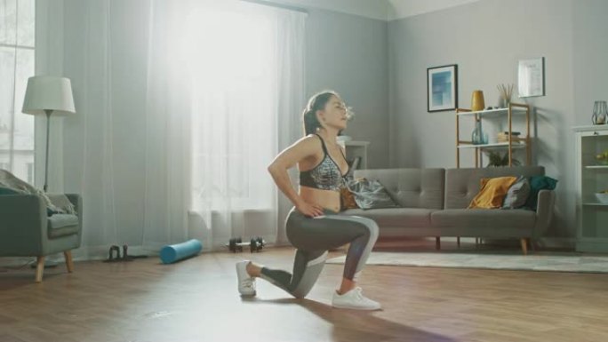 一个穿着灰色运动服的强壮健美女孩的延时镜头，在她明亮宽敞的客厅和简约的室内大力锻炼。