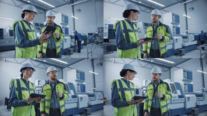 现代工厂: 女项目经理和男工程师站着穿着安全衣，安全帽，穿过车间，说话，使用数字平板和监控数控机械装