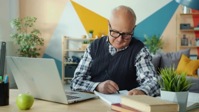 老人使用笔记本电脑打字上网在家做笔记