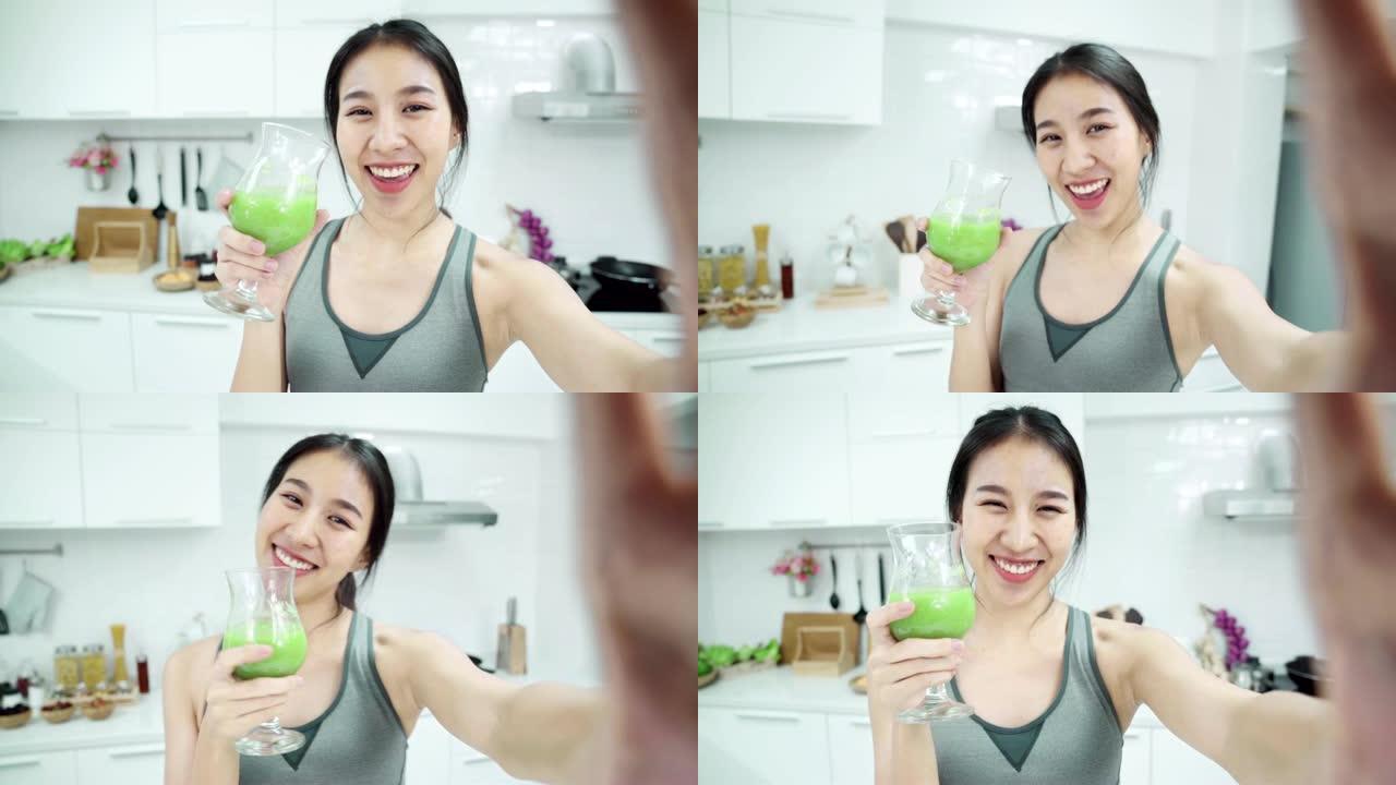POV: 年轻的亚洲女性在周末早上在厨房里使用智能手机，自拍和喝苹果的smooties。健康饮食和健