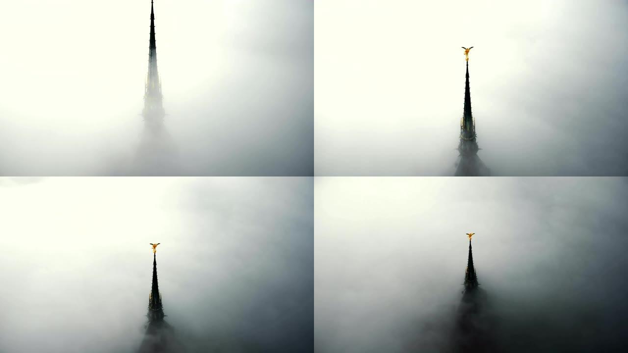 无人机在浓雾上方上升，在神秘的圣米歇尔山城堡尖顶上露出雄伟的金色天使雕像。