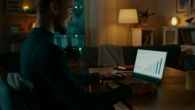 晚上在家: 男人在笔记本电脑上工作，显示统计信息图。舒适的客厅配有温暖的灯光。侧视图拍摄。