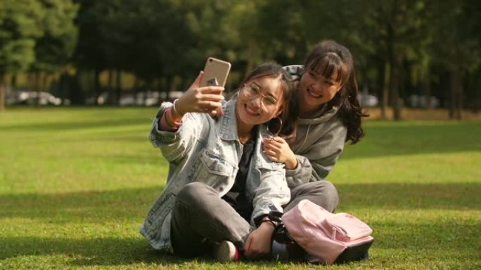 两名亚洲大学女生在校园内使用手机自拍