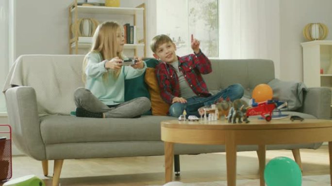 在家: 可爱的女孩在视频游戏机中玩耍，使用操纵杆控制器，她的年轻兄弟为她欢呼。玩电子游戏的快乐孩子。