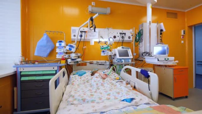 一个孩子用医疗机器睡在医院病房的床上。