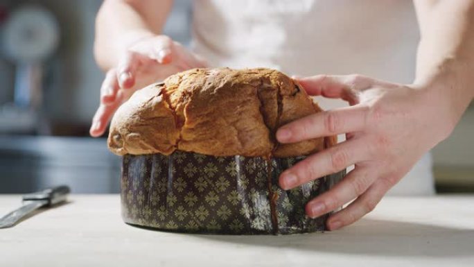 面包师的慢动作通过用手触摸意大利panettone来了解其柔软度，从而控制了意大利panettone