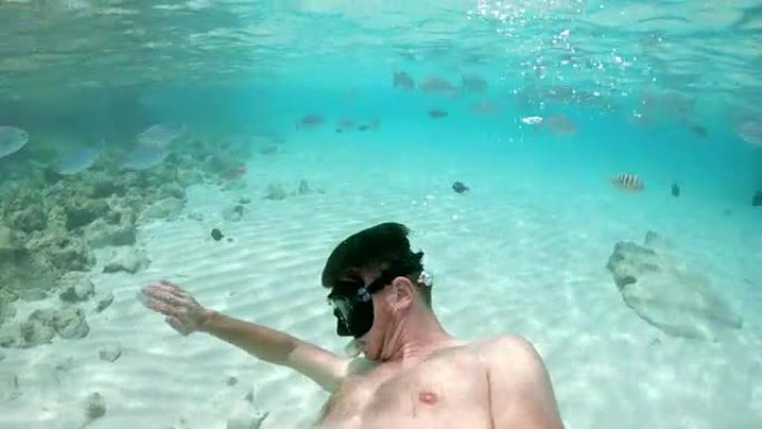 男子女士在马尔代夫热带海洋中使用可穿戴相机浮潜