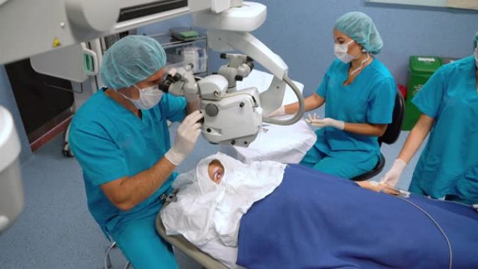 外科医生准备显微镜进行眼科手术，而团队正在准备其他仪器