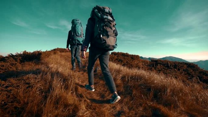 带着露营背包的徒步旅行者走向山顶。慢动作
