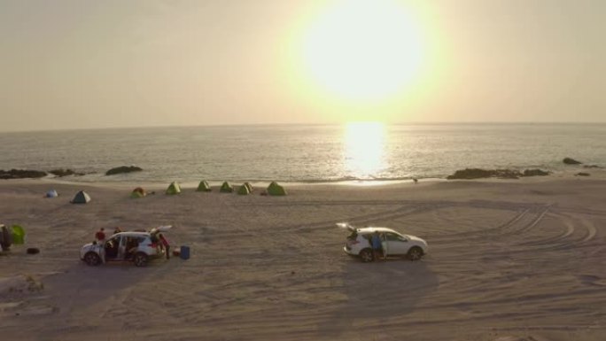 日落时在海滩上露营的空中游客