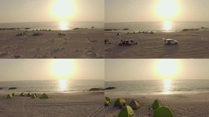 日落时在海滩上露营的空中游客