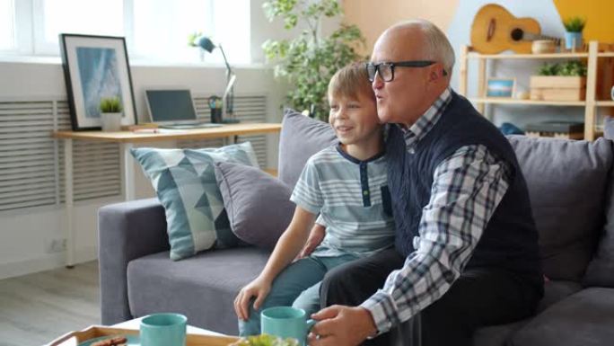 爷爷和孙子看电视的慢动作，零食在家里聊天