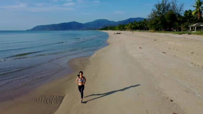 空中追踪拍摄运动慢跑者亚洲女子早上在海滩上跑步