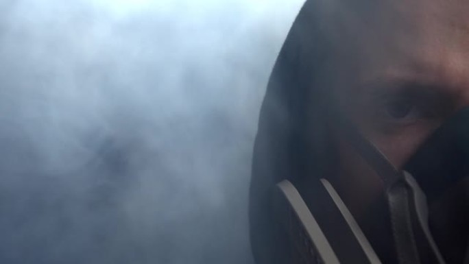 在他周围的烟雾中，保护面具中的人的脸特写。