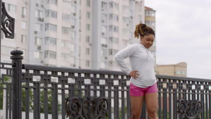 运动的黑人妇女在城市桥上做脊椎弯曲