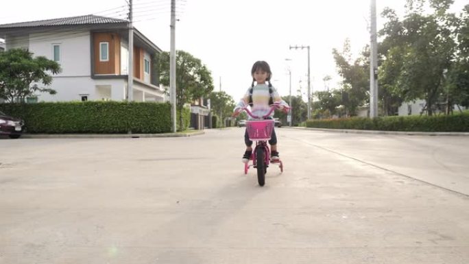 亚洲小女孩在街上骑自行车。