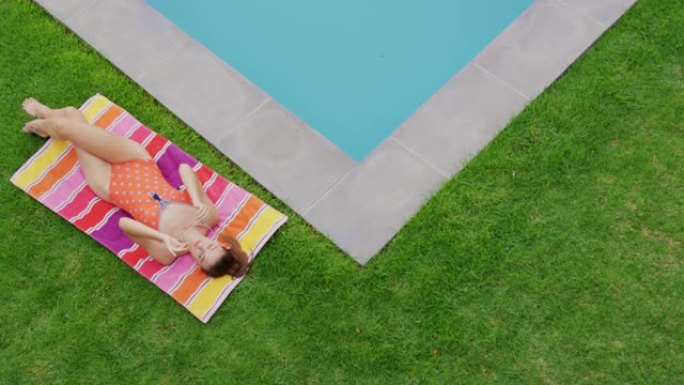穿着泳衣的女人放松在后院泳池边4k