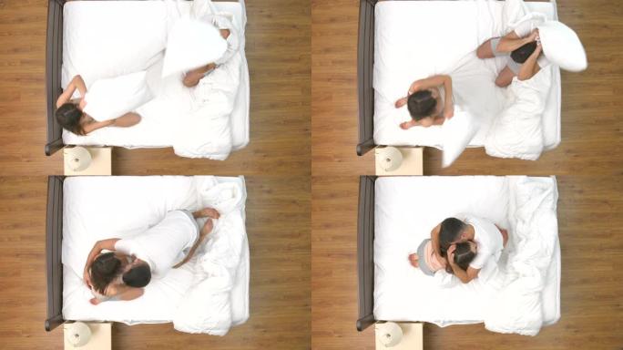 男人和女人在床上用枕头打架。从上方观看