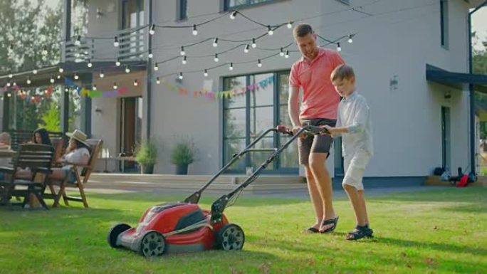 好父亲教儿子如何使用走在割草机后面，他们将其推到一起，割草。家人在阳光明媚的日子共度时光。
