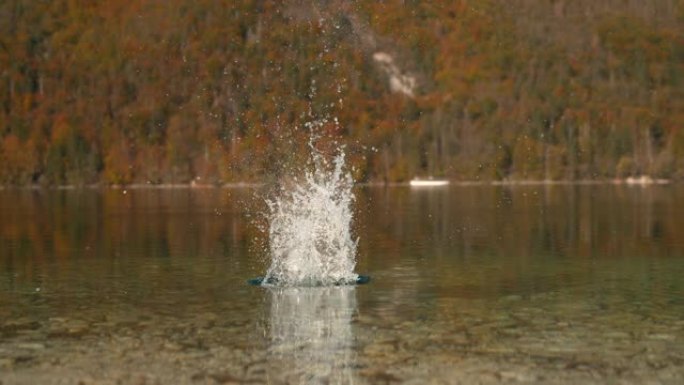 特写: 一块石头掉入湖中后，玻璃状的水在空中飞起来