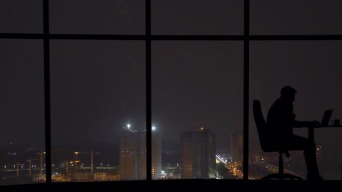 该男子在具有闪电背景的城市的全景窗户附近工作