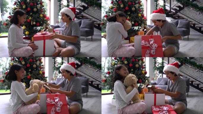 哥哥和姐姐坐在地板上，用玩具打开礼物，在圣诞节早上看书，微笑着说话