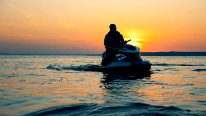 骑手坐在日落背景上的摩托艇上，近距离拍摄。