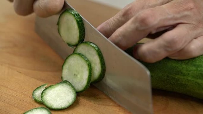 人用锋利的刀在厨房切割新鲜黄瓜