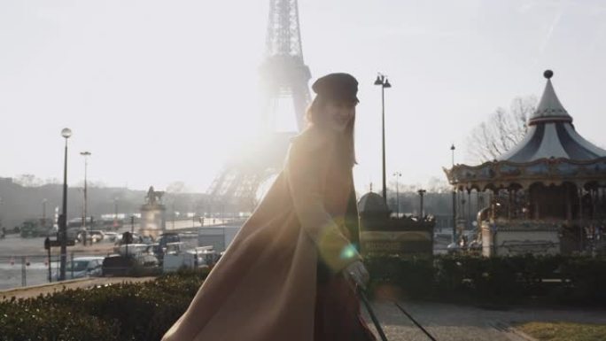 成功的快乐微笑美女散步，在阳光明媚的巴黎埃菲尔铁塔快乐地旋转度假慢动作。