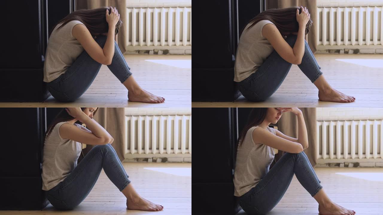 悲伤的女孩独自坐在地板上哭泣，感觉压力焦虑