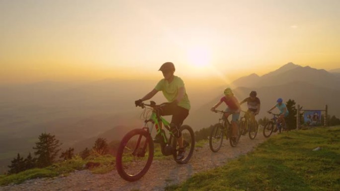 无人机: 快乐的游客在日落时骑着山地自行车沿着风景优美的小径行驶。