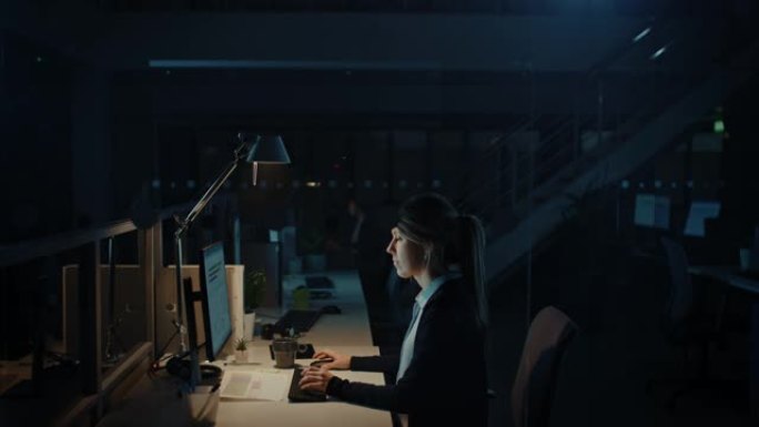 在办公室工作到深夜: 女商人使用台式计算机，分析，使用文档，解决问题，完成项目。