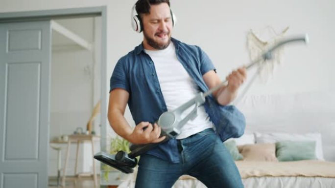 在公寓里假装弹吉他的快乐男人吸尘地毯的倾斜